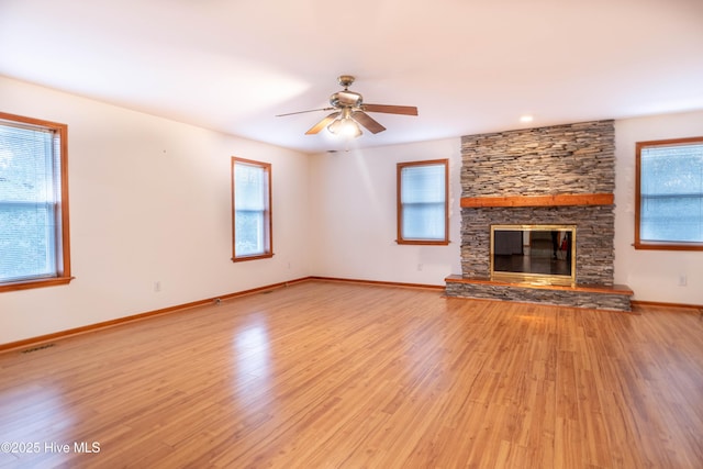 unfurnished living room featuring plenty of natural light, light wood-style flooring, and a stone fireplace