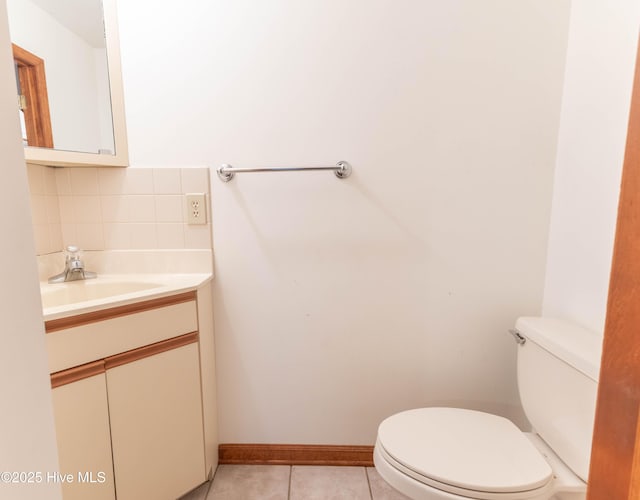 bathroom featuring toilet, vanity, baseboards, tile patterned floors, and tasteful backsplash