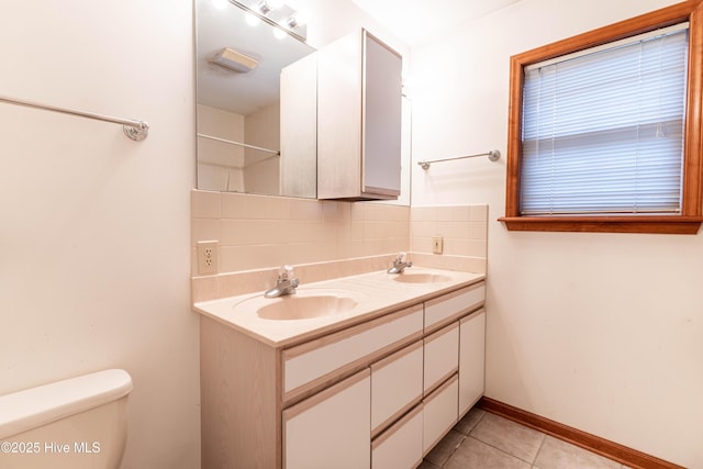 full bath with toilet, tasteful backsplash, a sink, and tile patterned floors