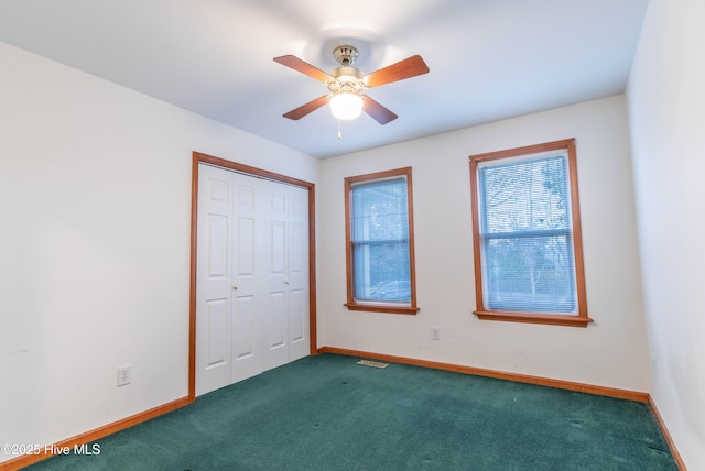 unfurnished bedroom with a closet, dark carpet, and baseboards