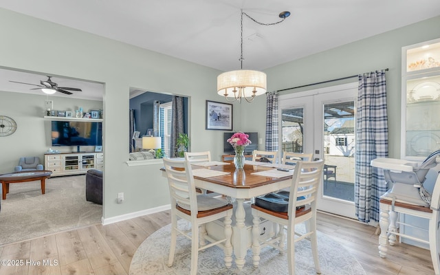 dining area featuring ceiling fan with notable chandelier, french doors, light wood-style flooring, and baseboards