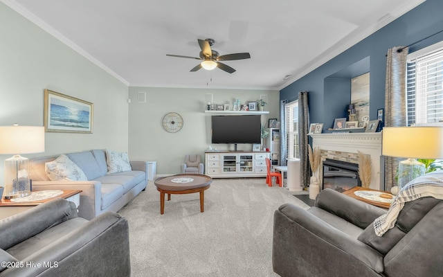 living area with ornamental molding, carpet, a fireplace with flush hearth, and a ceiling fan