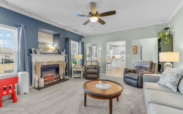 living room featuring light carpet, ornamental molding, a fireplace, and a ceiling fan