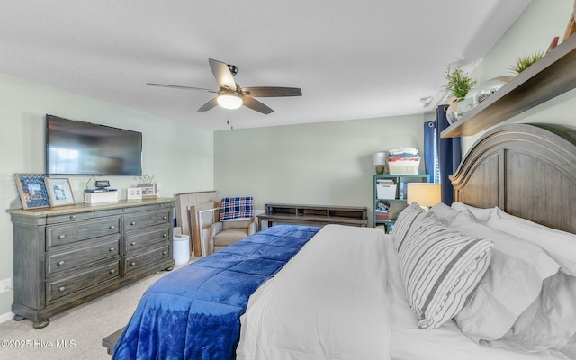 bedroom featuring light carpet, ceiling fan, and a textured ceiling