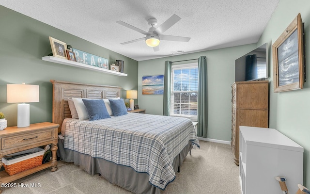 bedroom with a textured ceiling, a ceiling fan, visible vents, and light colored carpet