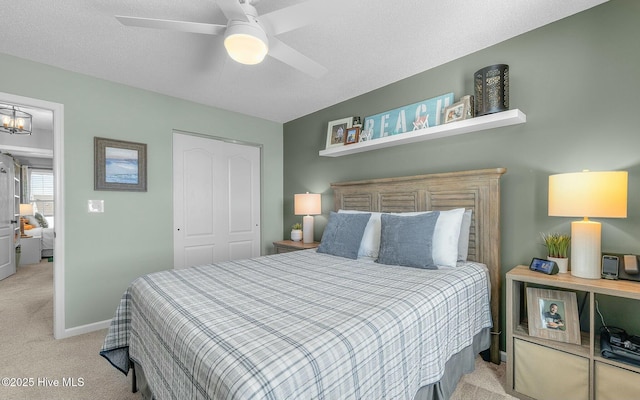 bedroom featuring a textured ceiling, light carpet, ceiling fan with notable chandelier, baseboards, and a closet