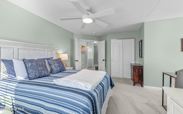 bedroom with a ceiling fan, a closet, light carpet, and a textured ceiling