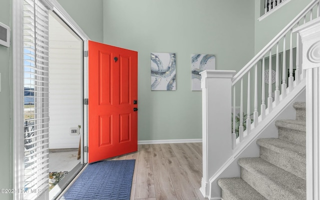 entryway with baseboards, stairs, and light wood-style floors