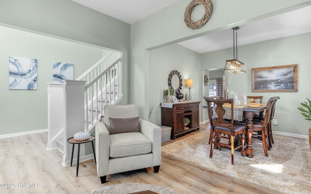 dining space with baseboards, light wood finished floors, and stairs