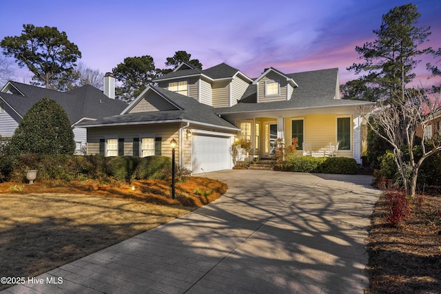 view of front facade with a garage, covered porch, a shingled roof, and concrete driveway