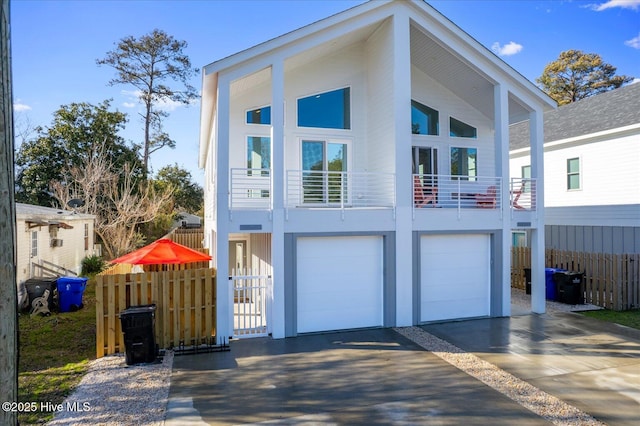 exterior space with driveway, a balcony, a garage, and fence