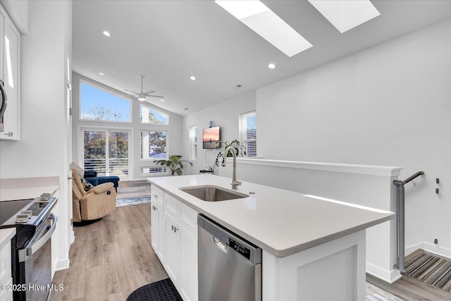 kitchen with electric range oven, stainless steel dishwasher, light wood-style floors, white cabinetry, and a sink