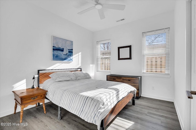 bedroom featuring a ceiling fan, wood finished floors, visible vents, and baseboards