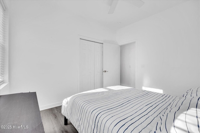 bedroom with a closet, wood finished floors, a ceiling fan, and baseboards