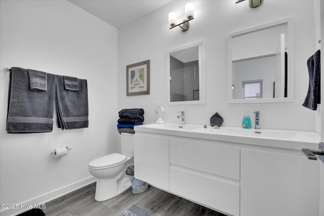 full bath featuring toilet, baseboards, a sink, and wood finished floors