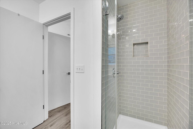 bathroom with a stall shower and wood finished floors