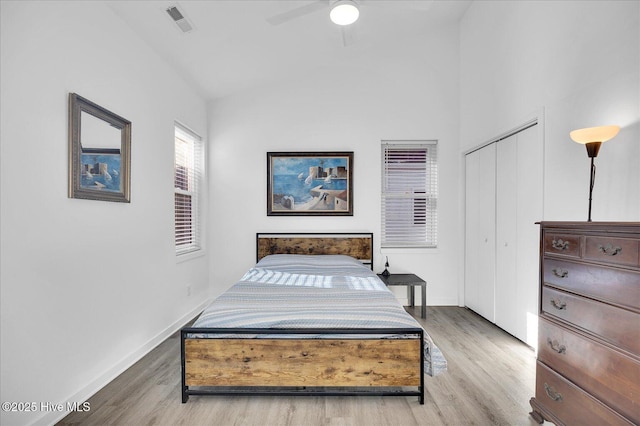 bedroom with a closet, visible vents, vaulted ceiling, and wood finished floors