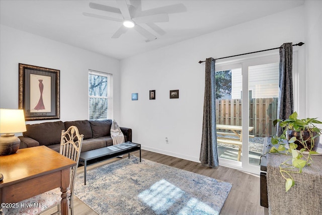 living area featuring ceiling fan, baseboards, and wood finished floors