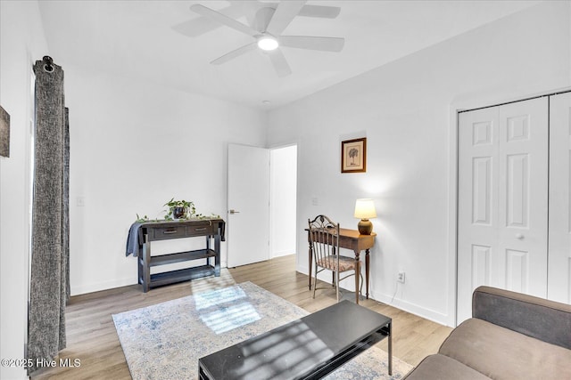 living room featuring a ceiling fan, light wood-style flooring, and baseboards