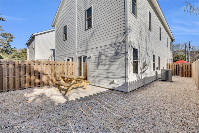 rear view of property with a fenced backyard and central air condition unit