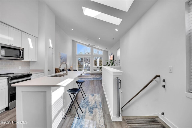 kitchen featuring light wood finished floors, white cabinetry, stainless steel appliances, and a sink