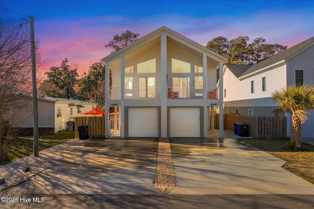 view of front of property with driveway, an attached garage, and fence