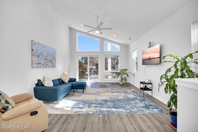 living room featuring high vaulted ceiling, plenty of natural light, baseboards, and wood finished floors