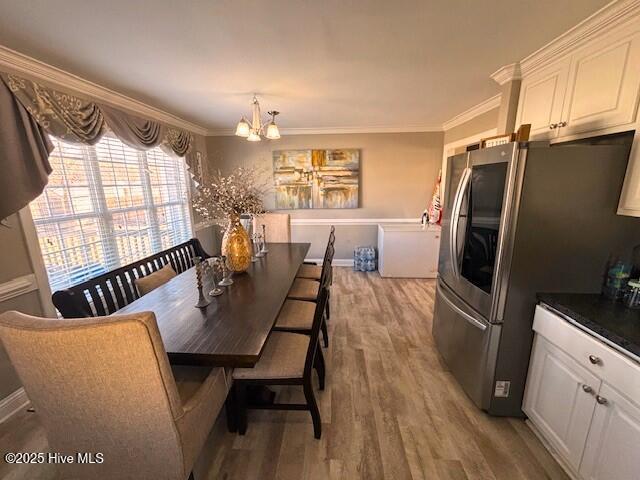 dining area with wood-type flooring, a chandelier, and crown molding