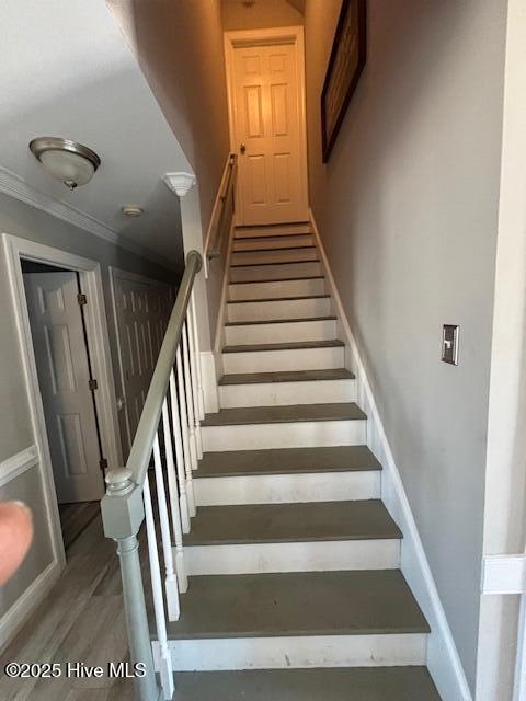 staircase featuring hardwood / wood-style flooring and ornamental molding