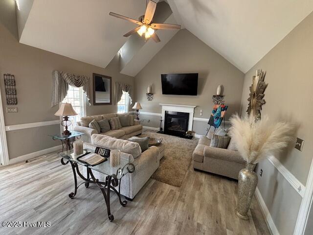 living room with light hardwood / wood-style floors, high vaulted ceiling, and ceiling fan