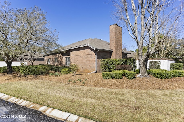 view of property exterior featuring a yard, brick siding, and a chimney