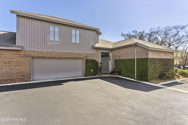 tri-level home featuring an attached garage, brick siding, driveway, and a shingled roof