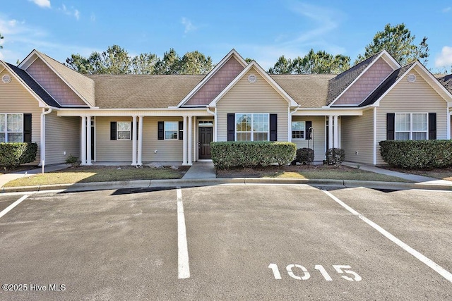 townhome / multi-family property featuring a shingled roof and uncovered parking