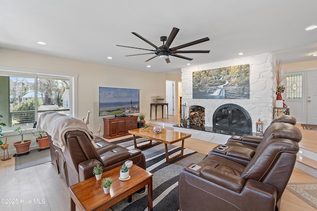 living room featuring ceiling fan and a stone fireplace