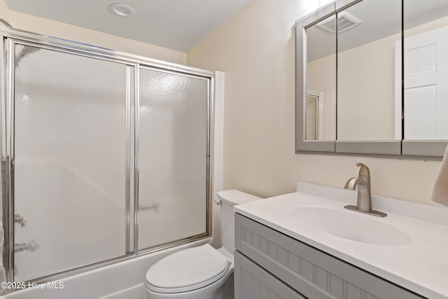 full bathroom with bath / shower combo with glass door, vanity, and toilet