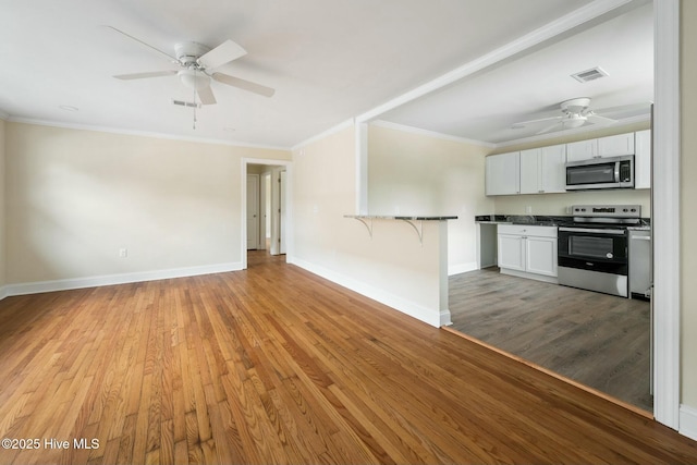 interior space featuring white cabinetry, crown molding, kitchen peninsula, and appliances with stainless steel finishes