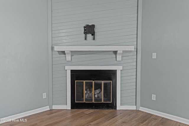 interior details featuring baseboards, wood finished floors, and a fireplace