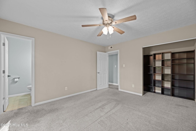unfurnished bedroom featuring ensuite bath, a textured ceiling, baseboards, and carpet floors
