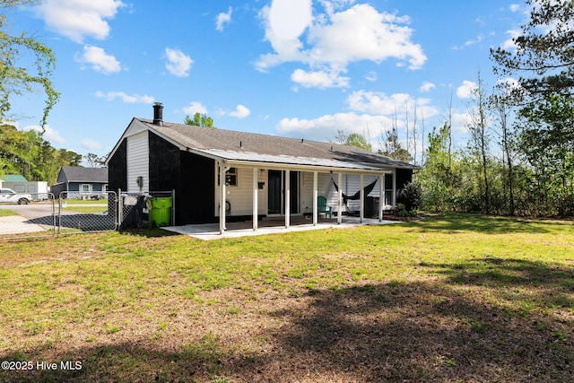back of property with a yard, a gate, fence, and a patio