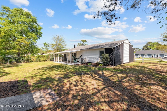 rear view of property featuring a patio area, fence, and a lawn