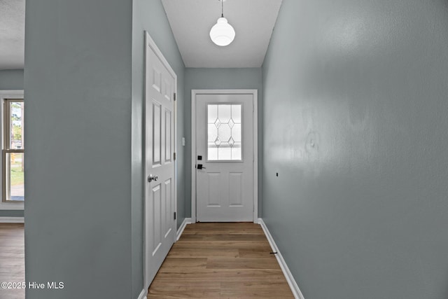 doorway to outside featuring wood finished floors and baseboards