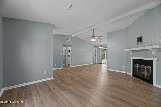 unfurnished living room featuring a large fireplace, visible vents, ceiling fan, vaulted ceiling with beams, and wood finished floors