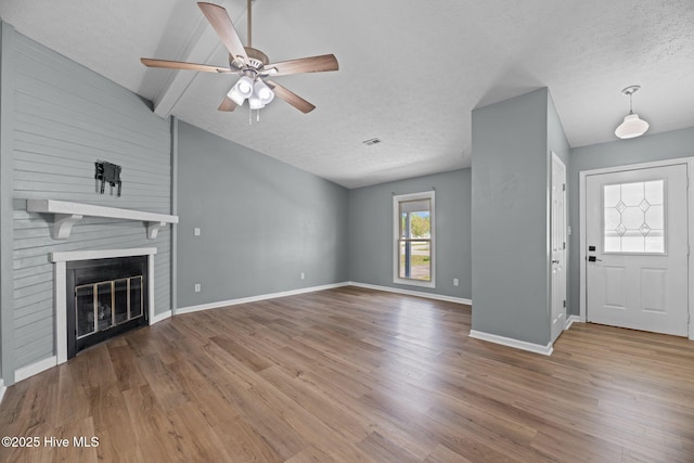 unfurnished living room with a textured ceiling, wood finished floors, baseboards, and a ceiling fan