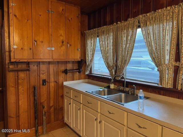 kitchen with light tile patterned floors, sink, and wooden walls