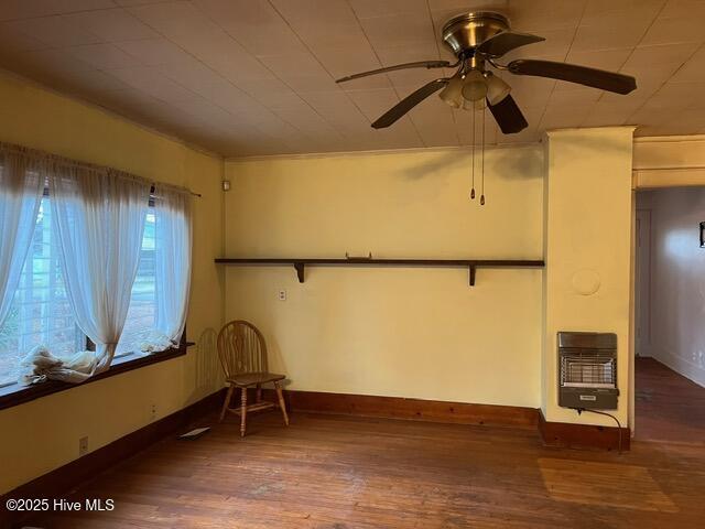 unfurnished room featuring hardwood / wood-style floors, heating unit, and ceiling fan