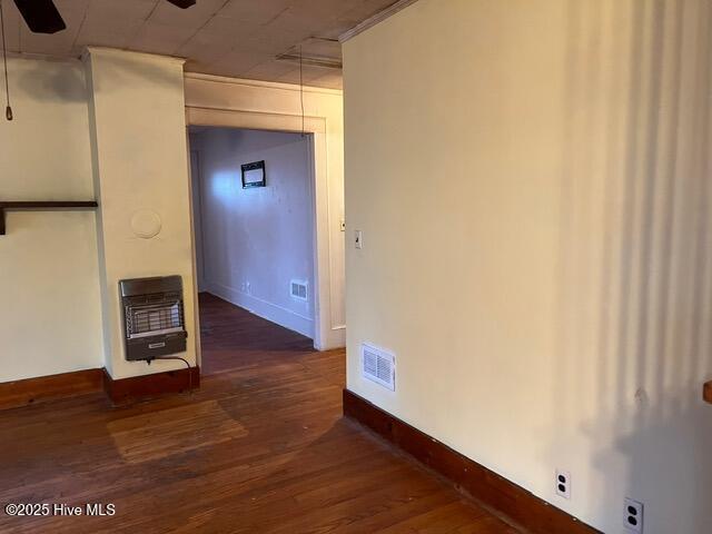 empty room with heating unit and dark hardwood / wood-style floors