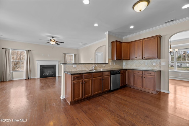 kitchen featuring visible vents, brown cabinets, a peninsula, a sink, and stainless steel dishwasher