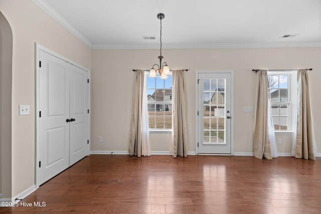 unfurnished dining area with a healthy amount of sunlight, visible vents, arched walkways, and wood finished floors