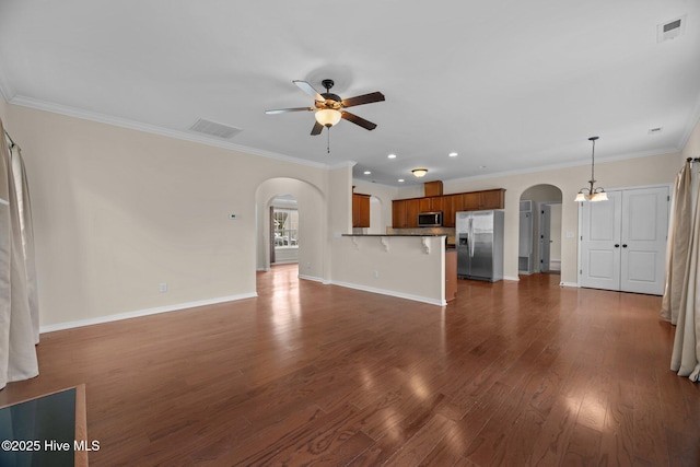 unfurnished living room with dark wood-style floors, arched walkways, visible vents, and a ceiling fan