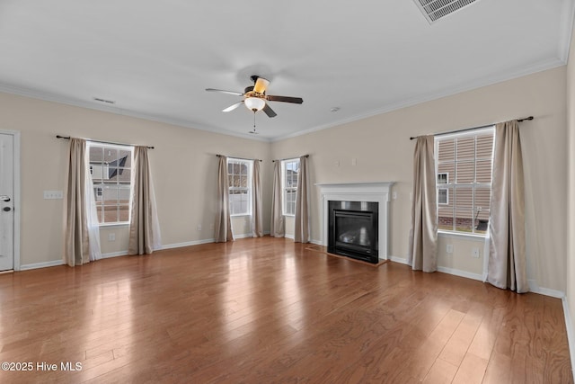 unfurnished living room featuring visible vents, a glass covered fireplace, ceiling fan, ornamental molding, and hardwood / wood-style floors